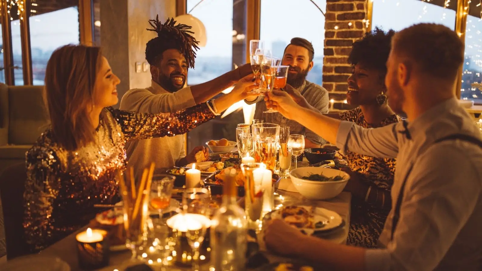 Friends toasting drinks at candlelit dinner party